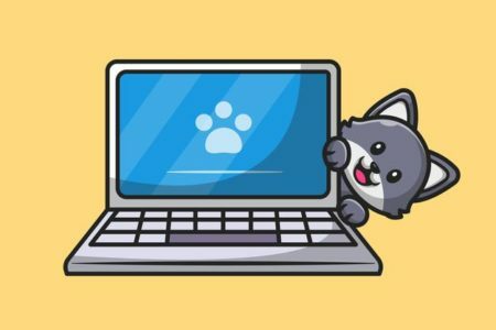 Chat mignon se cachant derrière un ordinateur portable